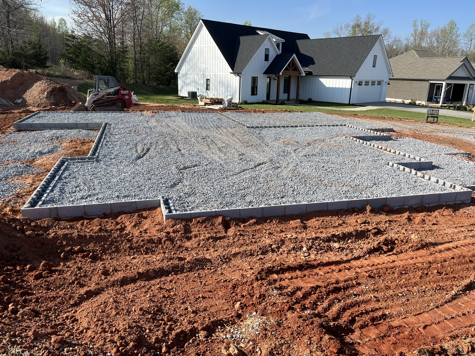 Base de grava compactada para cimentación de una casa nueva en un lote en ladera