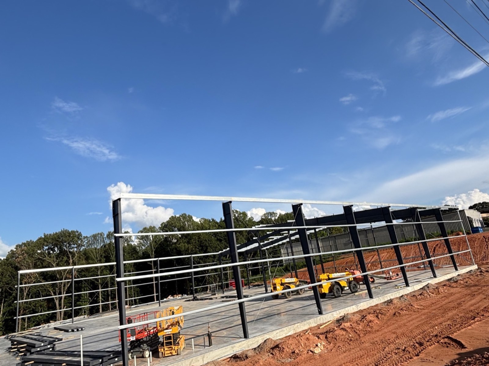 Steel columns and roof framing rising over a finished slab on a graded commercial pad