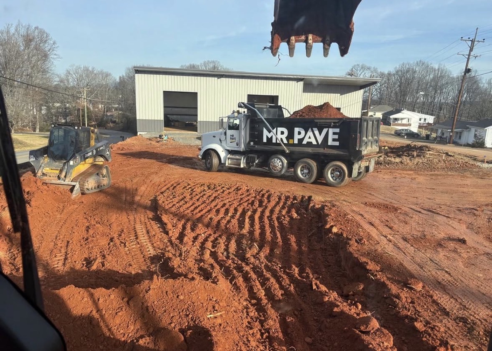 Mr. Pave branded dump truck being loaded by an excavator on an active jobsite