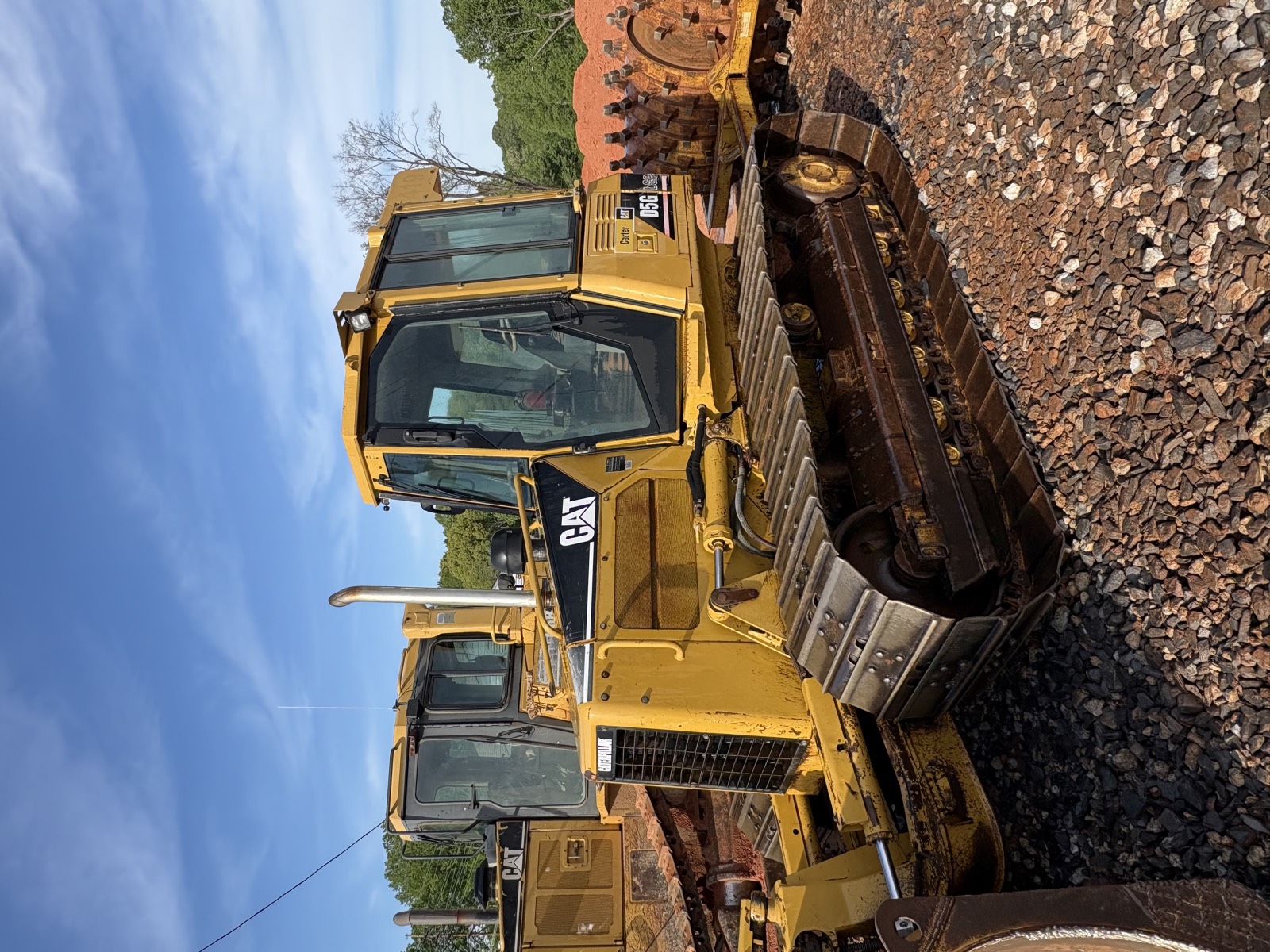 CAT dozer undercarriage and bucket staged on a red-clay excavation site