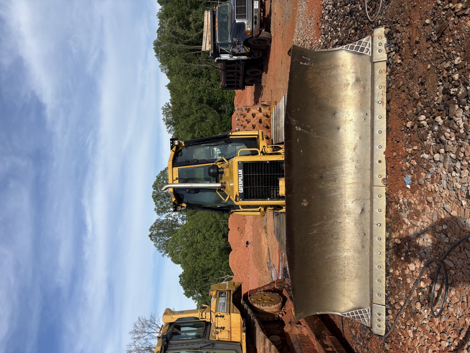 Oxen Civil dozer blade grading a site with a Mr. Pave truck staged in the background