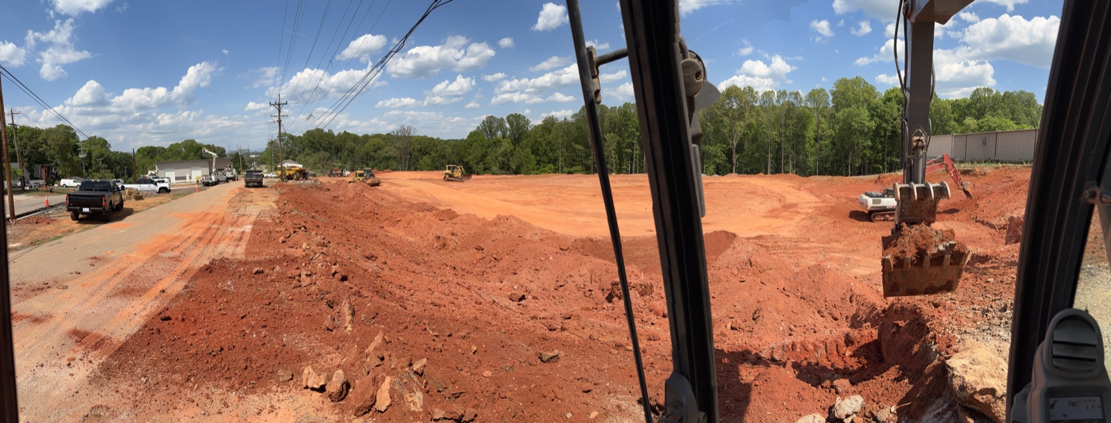 Excavadora, bulldozer, y camión de volteo en un sitio activo de tierra roja